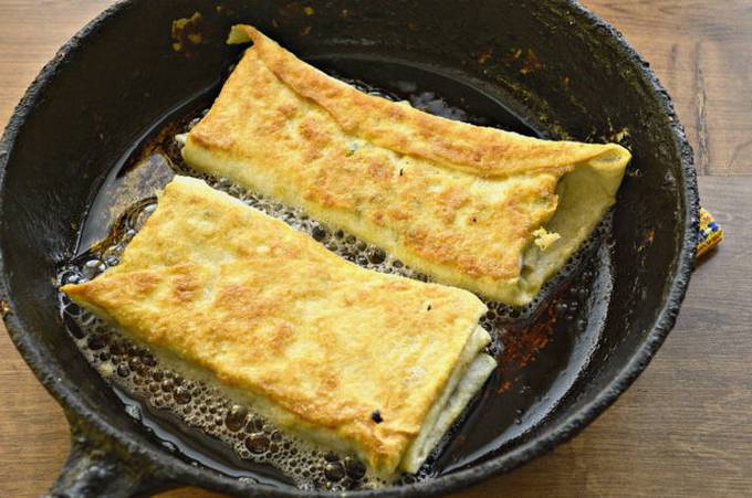Lavash-Umschläge mit Hüttenkäse, Käse und Kräutern in einer Pfanne