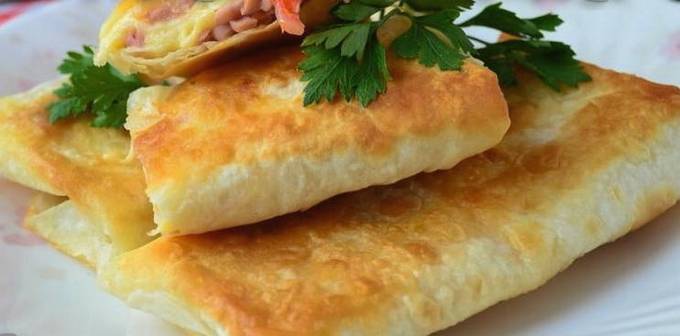 Lavash-Umschläge mit Wurst, Tomaten und Käse in einer Pfanne