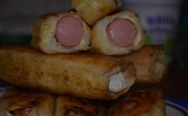 Würstchen mit Kartoffeln und Käse in Fladenbrot in einer Pfanne