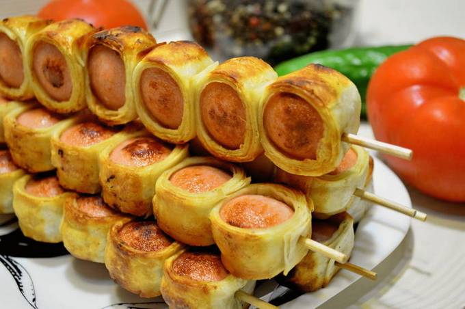 Würstchen in Fladenbrot am Spieß in einer Pfanne