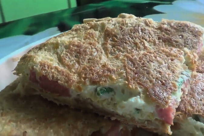 Würstchen in Fladenbrot mit Ei und Käse in einer Pfanne