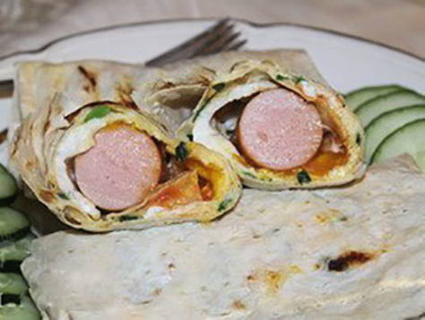 Würstchen in Fladenbrot mit Ei in einer Pfanne