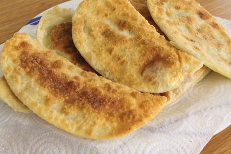 Chebureks mit in einer Pfanne gebratenen Kartoffeln