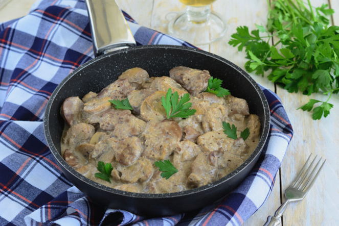 Fegatini di pollo in panna acida con cipolle e funghi in padella