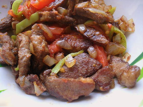 Schweinefleischstücke mit Gemüse in einer Pfanne
