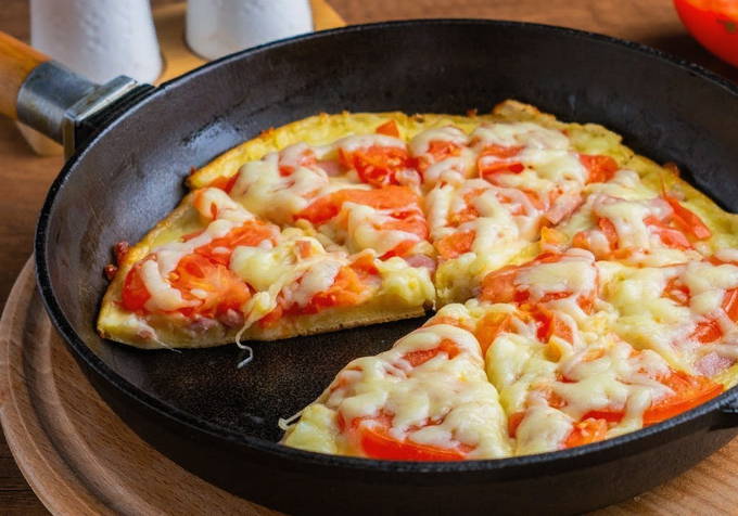 Pizza med pølse, tomater og ost i en gryde