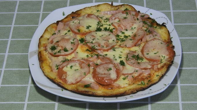 Pizza mit Würstchen, Tomaten und Käse in einer Pfanne