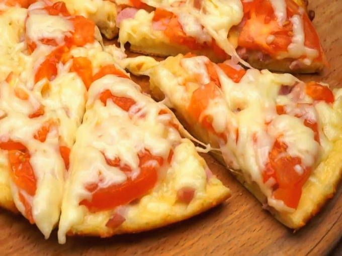 Schnelle Pizza mit Wurst und Käse und Tomaten in einer Pfanne