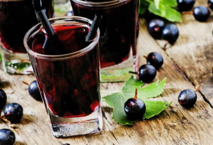 Schwarzer Johannisbeersaft durch einen Entsafter für den Winter